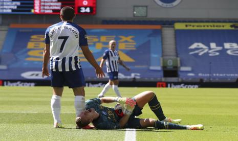 Kiper Arsenal Bernd Leno (kanan) mengerang kesakitan setelah bertabrakan dengan penyerang Brighton Neal Maupay (kiri).