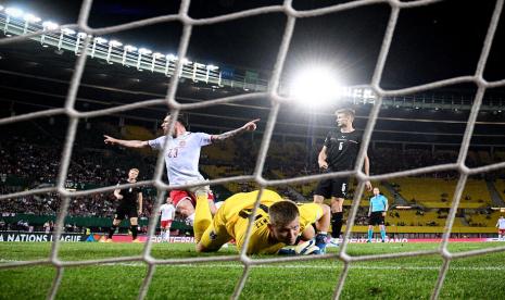 Kiper Austria Patrick Pentz terbaring di rumput menyaksikan gawangnya dibobol gelandang Denmark Pierre-Emile Hoejbjerg (kiri)  dalam pertandingan UEFA Nations League. Austria kalah 1-2 pada laga ini.