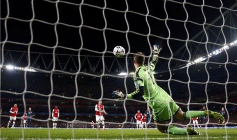 Kiper Bayern Muenchen, Manuel Neuer (kanan), menggagalkan tembakan penalti playmaker Arsenal, Mesut Oezil (tengah), dalam leg pertama babak 16 besar Liga Champions di Stadion Emirates, London, Rabu (19/2). 