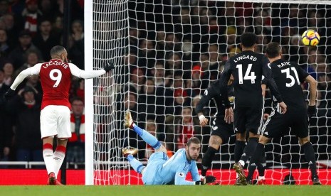 Kiper Manchester United, David De Gea (tengah) menggagalkan upaya striker Arsenal, Alexandre Lacazette mencetak gol pada laga Liga Primer Inggris, di Stadion Emirates, Sabtu (2/12).