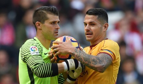 Kiper Sporting Gijon, Ivan Cuellar (kiri) berebut bola dengan striker Sevilla, Vitolo pada laga La Liga di stadion El Molinon, Sabtu (29/10). Hasil laga berakhir imbang 1-1.