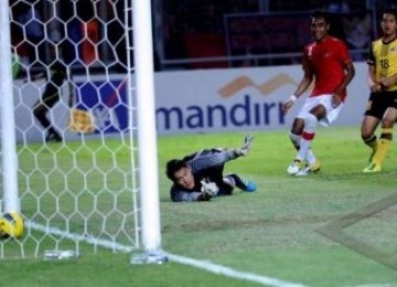 Kiper timnas Indonesia Andritany Ardhiyasa (kiri) tak kuasa menahan laju bola tendangan pesepakbola Malaysia Ibrahim Syahrul Azwari (kanan) yang berbuah gol saat pertandingan lanjutan babak kualifikasi Grup A SEA Games XXVI Indonesia di Stadion Utama Gelor