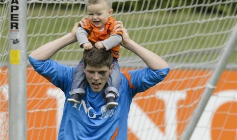 Klaas-Jan Huntelaar, striker timnas Belanda, menggiring bola sambil menggendong anaknya Axel usai menggelar sesi pertama latihan timnas di Lausanne, Swiss, Jumat (18/5).  