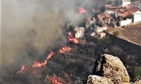 Kobaran api membakar hutan di dekat perumahan warga di El Rincon, Tejeda di Pulau Gran Canaria, Spanyol, Ahad (18/8).