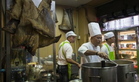 Koki memasak di dekat sirip hiu yang sudah dikeringkan. Diperkirakan 73 juta hiu dibunuh demi kebutuhan konsumsi sirip hiu.