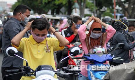 Warga memasang masker kain. Kelembapan dan gesekan akibat pemakaian masker dapat menyebabkan kulit telinga menjadi iritasi.