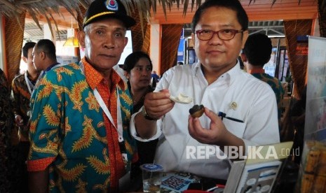 Komunikasi dan Informatika Rudiantara mencoba telur asin saat peluncuran Program Sinergi Aksi untuk Ekonomi Rakyat di Desa Larangan, Kecamatan Larangan, Brebes, Jawa Tengah, Senin, (11/4). (Republika/Agung Supriyanto)