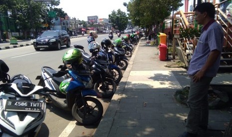 Kondisi bahu jalan di depan Mall Tamini Square, Jakarta Timur terlihat seperti parkir liar. Hal ini disebabkan oleh banyaknya kendaraan bermotor yang parkir di bahu jalan tersebut.  Kebanyakan dari mereka yang memarkir di bahu jalan ini adalah para pengemudi ojek online. 