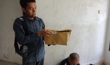 Koordinator Divisi Pengawasan Bawaslu Kabupaten Purwakarta, Oyang Este Binos (kemeja warn navy) memerlihatkan segel logistik KPU yang rusak, saat dilakukan pengepakan surat suara oleh petugas, Senin (1/4). 