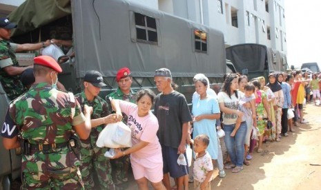 Anggota Kopassus membagikan paket sembako untuk korban banjir di rumah susun Penjaringan Muara Baru ,Jakarta Utara,Kamis (7/2).  (dok. Penerangan Kopassus)