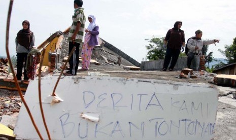   Korban Gempa berdiri diantara puing-puing bangunan rumahnya yang rusak akibat gempa bumi di Desa Blang Mancung Bawah, Ketol, Aceh Tengah, Aceh, Jumat (5/7).    (Antara/Irwansyah Putra)