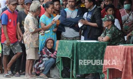 Korban gempa bumi dan tsunami antre untuk mendapatkan bantuan di salah satu posko di Palu, Sulawesi Tengah, Ahad (7/10). 