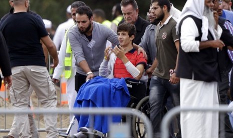 Korban selamat penembakan di Masjid Christchurch, Zaed Mustafa (di kursi roda) saat berada di pemakaman adiknya Hamza dan ayahnya Khalid Mustafa di Memorial Park Cemetery, Christchurch, Selandia Baru, Rabu (20/3).