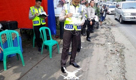 Korlantas Polri AKP Taufik Syahrial menerbangkan drone untuk mengambil gambar untuk bahan penyidikan kecelakaan maut di Jalan Raya Puncak, Turunan Selarong, Cipayung, Megamendung, Kabupaten Bogor, Ahad (23/4). 