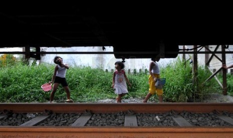 Kurang Lahan Bermain. Beberapa anak bermain mencari ikan pada genangan air tepian rel kereta api di kawasan Kampung Bandan, Jakarta, Jumat (21/3).