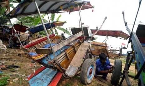 Kusir memperbaiki roda delman sebelum digunakan untuk bekerja di Jakarta, Rabu (20/8).(Republika/ Wihdan)