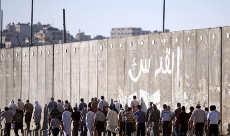 Laki-laki Palestina melintas disamping tembok pemisah Israel dalam perjalanan mereka untuk shalat Jumat di Masjid Al Aqsa di Yerusalem, Jumat (10/8). (Majdi Muhammad/AP)