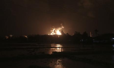 Langit bersinar dari api yang menghanguskan kilang minyak milik perusahaan minyak nasional Pertamina, di Cilacap, Jawa Tengah, Indonesia, Sabtu, 13 November 2021.