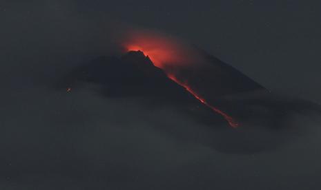 Lava mengalir dari kawah Gunung Merapi terlihat dari desa Pakembinangun di Sleman, Jawa Tengah, Kamis, 10 Maret 2022. Gunung Merapi Indonesia memuntahkan awan panas dalam letusan semalam Kamis yang memaksa sekitar 250 warga mengungsi ke tempat penampungan sementara. Tidak ada korban yang dilaporkan.