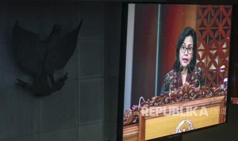 Layar yang menampilkan Menteri Keuangan Sri Mulyani Indrawati menyampaikan pandangan akhir Pemerintah pada Rapat Paripurna DPR di Kompleks Parlemen Senayan, Jakarta, Kamis (26/7). 