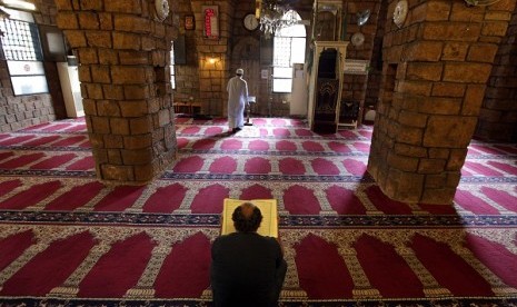 Lebanese men pray and read the Quran, the Muslim holy book, at a mosque in Beirut, Lebanon, Wednesday, July 10, 2013. 