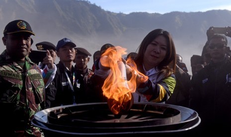 Legenda bulu tangkis Indonesia Susi Susanti (tengah) menyalakan kaldron dengan obor Asian Games 2018 saat prosesi Torch Relay Asian Games 2018 di lautan pasir Gunung Bromo, Probolinggo, Jawa Timur, Sabtu (21/7). 