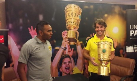 Legenda Dortmund, Karl-Heinz Riedl (baju kuning) dan Managing Director Dortmund untuk kawasan Asia, Suresh Letchmanan berfoto dengan trofi DFB Pokal 2017 di Hotel Sultan, Jakarta pada Selasa (10/10) pagi WIB. Dortmund mengunjungi Jakarta untuk merangkul pecinta sepak bola di IndonesiaR