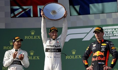 Lewis Hamilton (kiri) menyaksikan Valtteri Bottas mengangkat trofi juara GP Australia 2019.