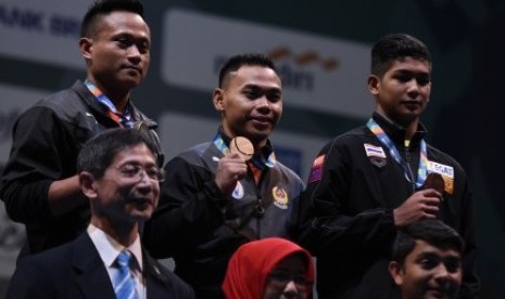 LIfter Indonesia Eko Yuli Irawan (tengah) bersama Muhamad Purkon (kiri) dan lifter Thailand Jettarin Sriram menunjukkan medali yang mereka dapat pada nomor putra 62 kg 18th Asian Games Invitation Tournament di JiExpo, Jakarta, Ahad (11/2). 