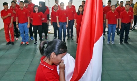 Lifter pelatnas Asian Games Indonesia Sri Wahyuni mencium bendera dalam acara pembacaan ikrar dan kebulatan tekad atlet di Jakarta, Senin (8/1). Cabang angkat besi ditargetkan meraih satu medali emas dalam Asian Games 2018.