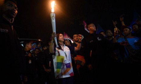 Lilis Handayani, mantan atlet panahan Indonesia, membawa obor para Kirab Obor Asian Games 2018 di Kota Malang, Jawa Timur.