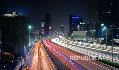 Lintasan sinar lampu mobil berpadu dengan lansekap kota malam hari di salah satu sudut kota Jakarta.