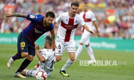 Lionel Messi berebut bola dengan pemain SD Huesca pada  pertandingan sepak bola La Liga Spanyol (2/9).