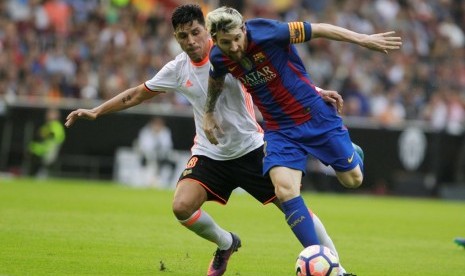 Lionel Messi (kanan) dijaga pemain Valencia Enzo Perez.