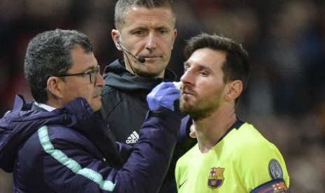 Lionel Messi (kanan) mendapatkan perawatan dokter dalam laga Manchester United vs Barcelona.