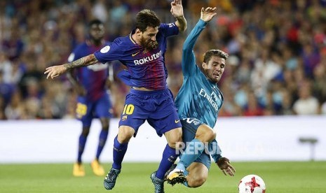 Lionel Messi (kiri) berduel dengan Mateo Kovacic (kanan) di leg pertama Final Piala Super Spanyol antara Barcelona vs  Real Madrid di Camp Nou, Barcelona, Senin (14/8) pagi. 