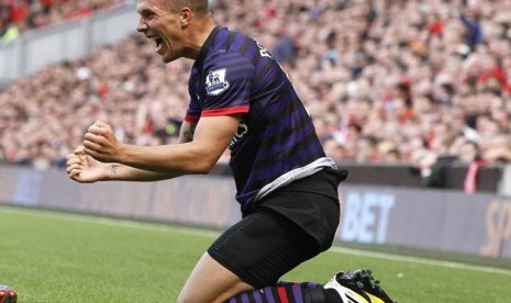 Lukas Podolski merayakan gol perdananya ke gawang Liverpool di Anfield, Ahad (2/9)