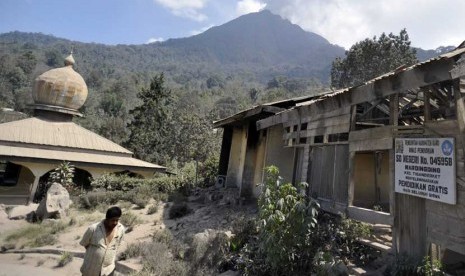 Seorang warga melintasi masjid dan sekolah dasar yang rusak akibat abu vulkanik Gunung Sinabung di Desa Mardinding, Karo, Sumut, Selasa (4/2).   (Antara/Wahyu Putro)