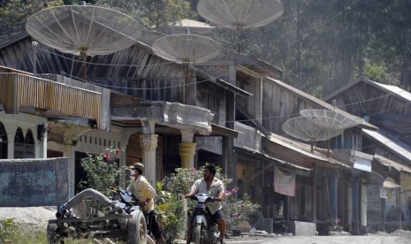   Dua warga melintasi sejumlah rumah yang diselimuti abu vulkanik Gunung Sinabung di Desa Mardinding, Karo, Sumut, Selasa (4/2).    (Antara/Wahyu Putro)