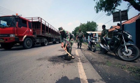   Sejumlah anggota TNI menambal jalan yang berlubang di jalur pantura Lohbener, Indramayu, Jawa Barat, Senin (10/2).    (Antara/Dedhez Anggara)