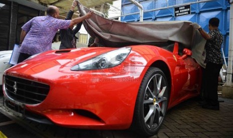   Petugas KPK melakukan perawatan terhadap mobil mewah milik tersangka Tubagus Chaeri Wardana alias Wawan di halaman Gedung KPK, Jakarta, Jumat (21/2).  (Republika/Agung Supriyanto)