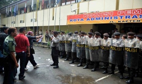  Petugas kepolisian menghalau para demonstran yang memaksa masuk ke kantor KPU saat simulasi pemilu di depan kantor KPU Jakarta Selatan, Jumat (21/2). (Republika/Agung Supriyanto)