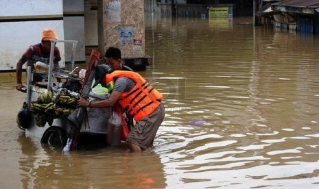 Warga berusaha menerobos genangan air di Jalan KH. Abdulah Syafei,Kampung Melayu Besar, Jakarta, Ahad (23/2). (Republika/Tahta Aidilla)