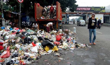 Seorang pengguna jalan melintasi sampah yang berserakan di bahu Jalan Matraman Raya, Jakarta Timur, Rabu (26/2).    (foto: Raisan Al Farisi)