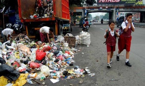   Dua orang anak melintasi sampah yang berserakan di bahu Jalan Matraman Raya, Jakarta Timur, Rabu (26/2).    (foto: Raisan Al Farisi)