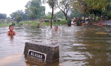   Sejumlah anak bermain air saat banjir melanda Tempat Pemakaman Umum (TPU) Karet Bivak, Tanah Abang, Jakarta Pusat, Kamis (27/2). (foto : Raisan Al Farisi)