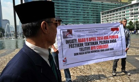    Relawan dari Gerakan Nasional Peduli Pemilu (Genapp) merentangkan spanduk sosialisasi Pemilu 2014 di Bundaran HI, Jakarta, Selasa (4/3). (Republika/Tahta Aidilla)