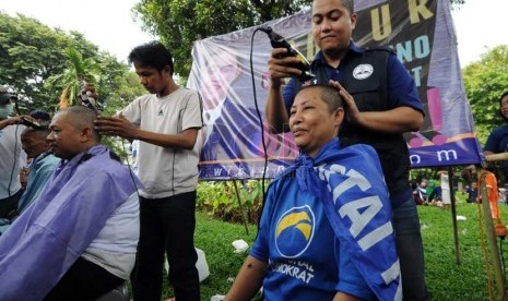  Salah seorang calon legislatif melakukan aksi potong rambut gratis dalam kampanye Partai Nasional Demokrat (Nasdem) di Kompleks Tugu Proklamasi, Jakarta, Ahad (16/3). (Republika/Aditya Pradana Putra)