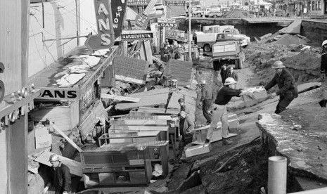 Dalam foto yang diambil pada 30 Maret 1964 lalu, warga membersihkan reruntuhan akibat gempa bumi di Alaska. (AP)