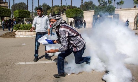   Pendukung Presiden terguling Muhammad Mursi mengambil tabung gas air mata yang ditembakkan oleh pasukan keamanan di Universitas Kairo, Giza, Mesir, Rabu (26/3).  (AP/Amru Taha)